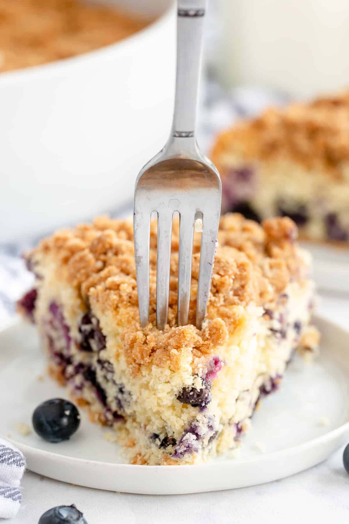 A fork presses into a slice of Blueberry Crumb Cake.