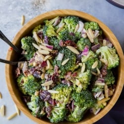 An over the top shot of a bowl of Broccoli Salad next to a purple cloth.