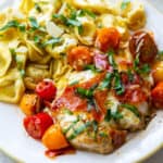 Chicken Caprese on a white plate with tortellini.