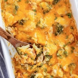 An over the top shot of a spoon resting in a casserole dish full of Chicken Broccoli Rice Casserole.