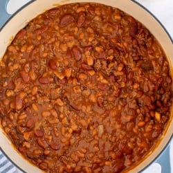 A blue Dutch oven filled with baked beans shot from over the top.
