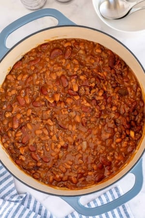 A blue Dutch oven filled with baked beans shot from over the top.