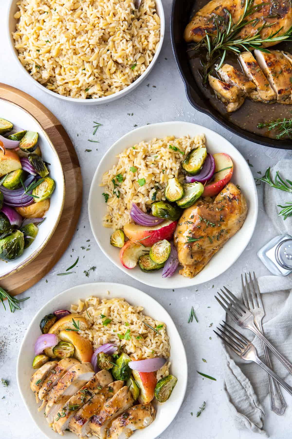 Two bowl of Apple Cider Chicken next to bowls of rice and vegetables.