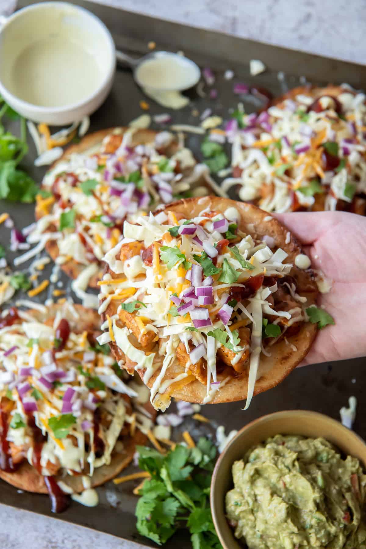 A hand lifts a tostada from a baking sheet.