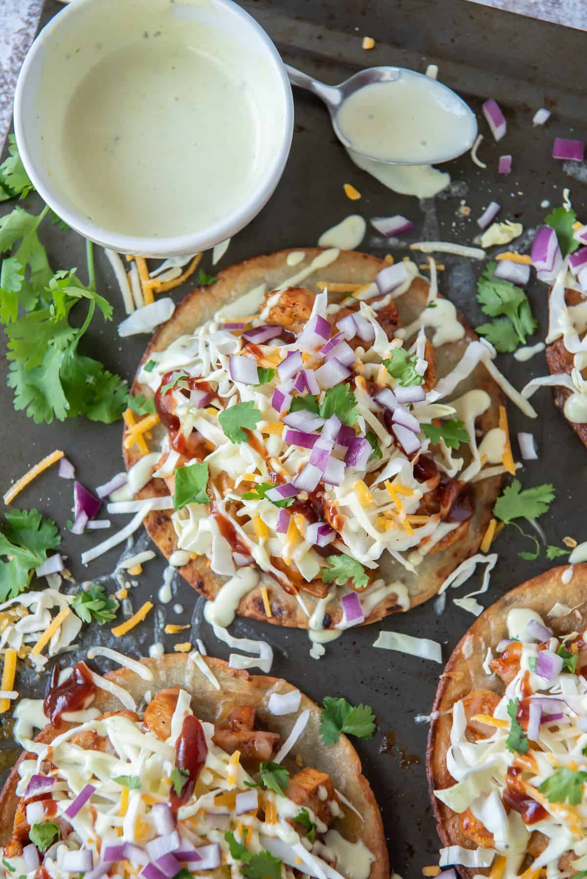 Tostadas and a small bowl of salad dressing on a baking sheet.