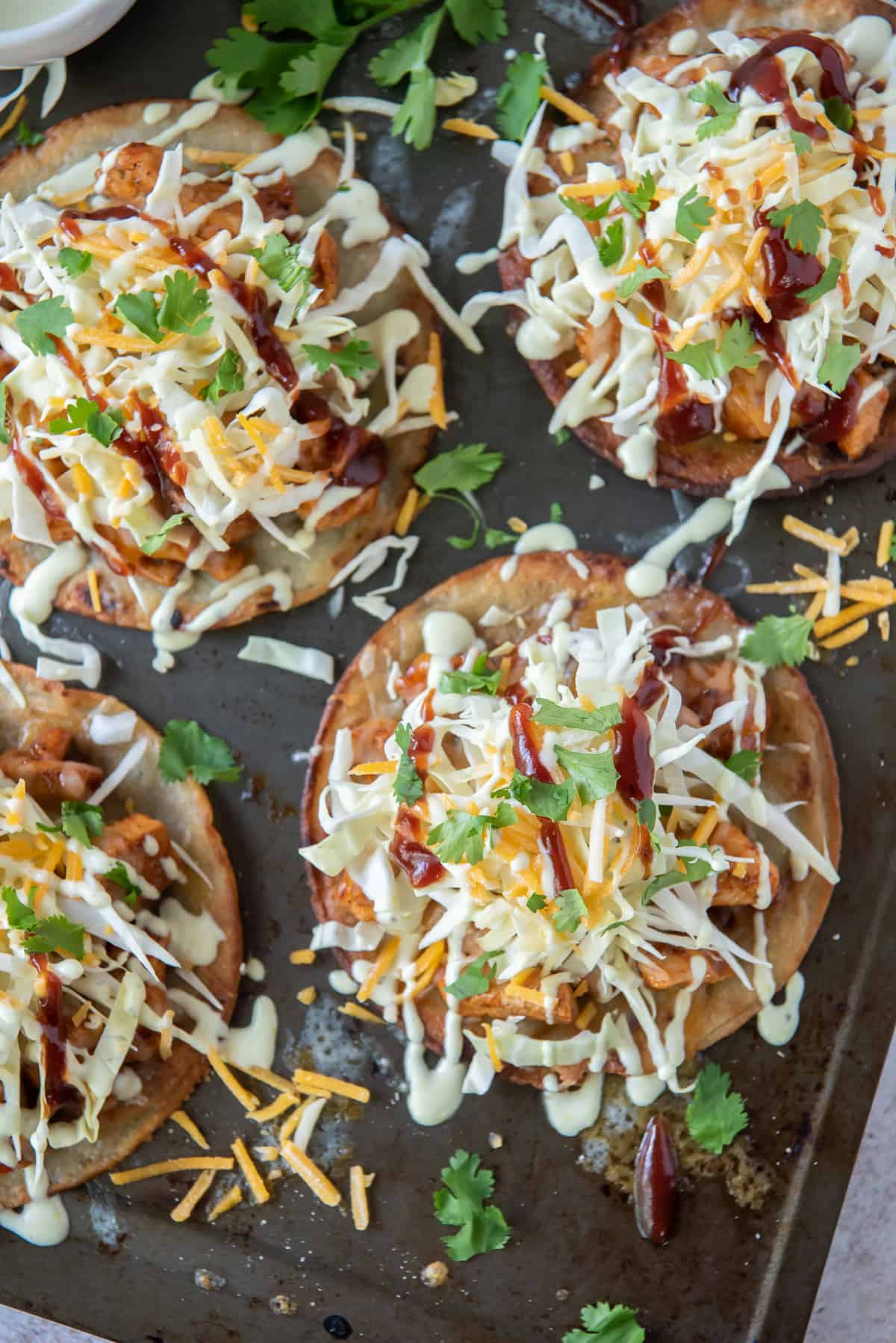 Four BBQ Chicken Tostadas on a baking sheet.