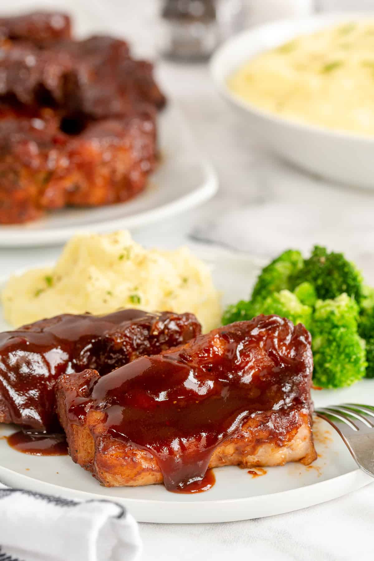 Country Style Ribs on a plate with mashed potatoes and broccoli.