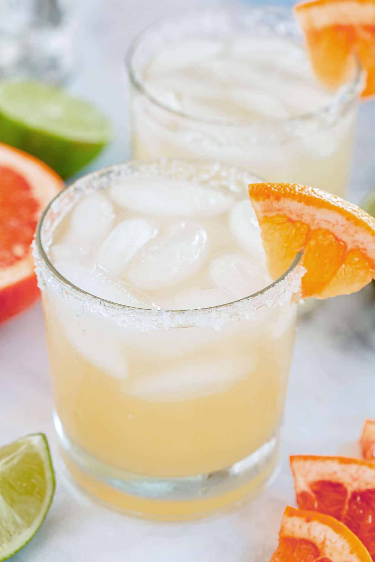 A close up of a paloma cocktail in a lowball glass with a grapefruit garnish.