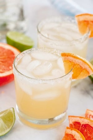 A paloma cocktail in a small glass with a grapefruit wedge on the rim.