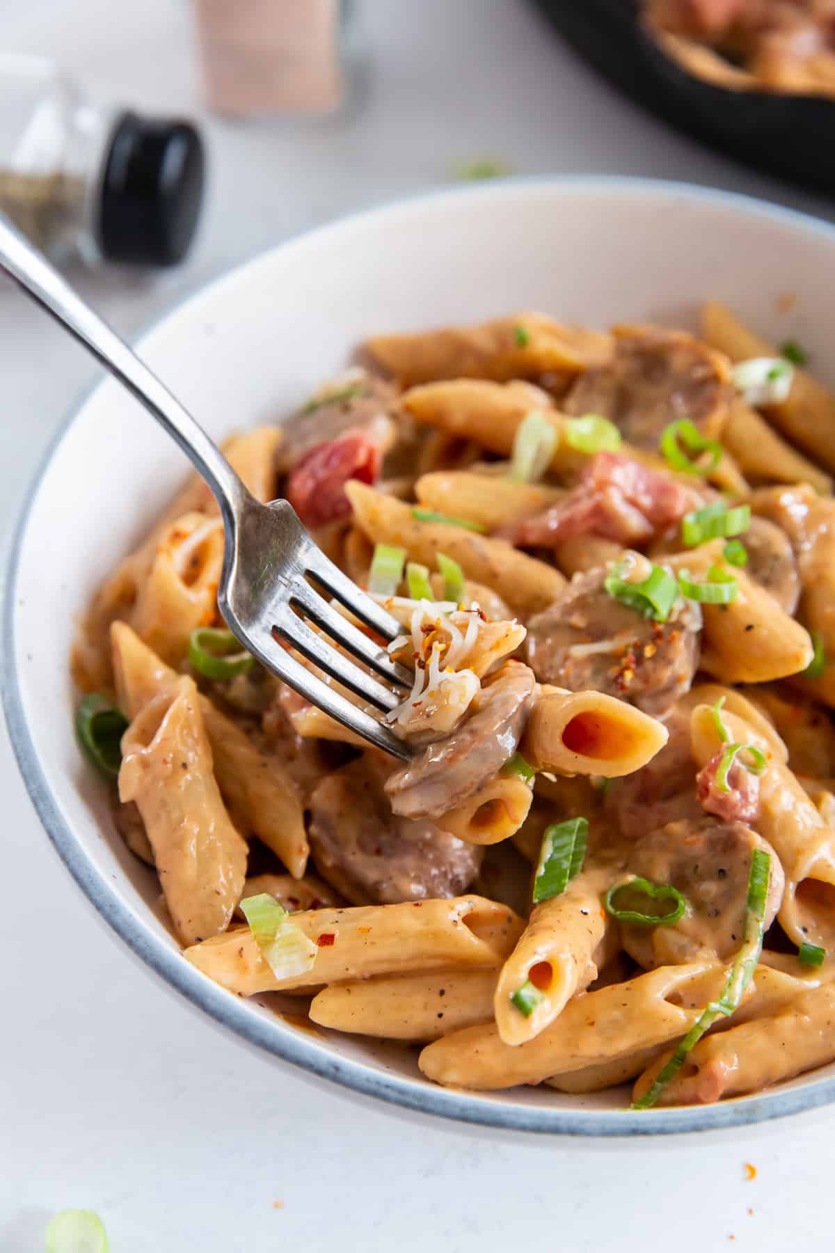 A fork digging into a bowl of Skillet Sausage Pasta.