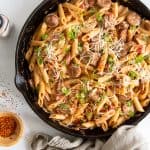 An over the top shot of sausage pasta in a cast iron skillet.