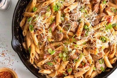 An over the top shot of sausage pasta in a cast iron skillet.