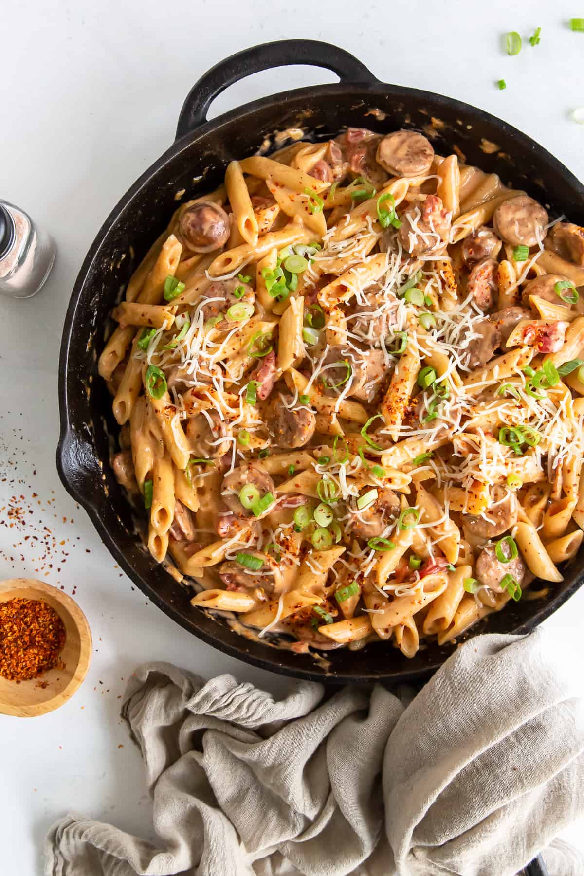 An over the top shot of a cast iron skillet filled with pasta and sausage.