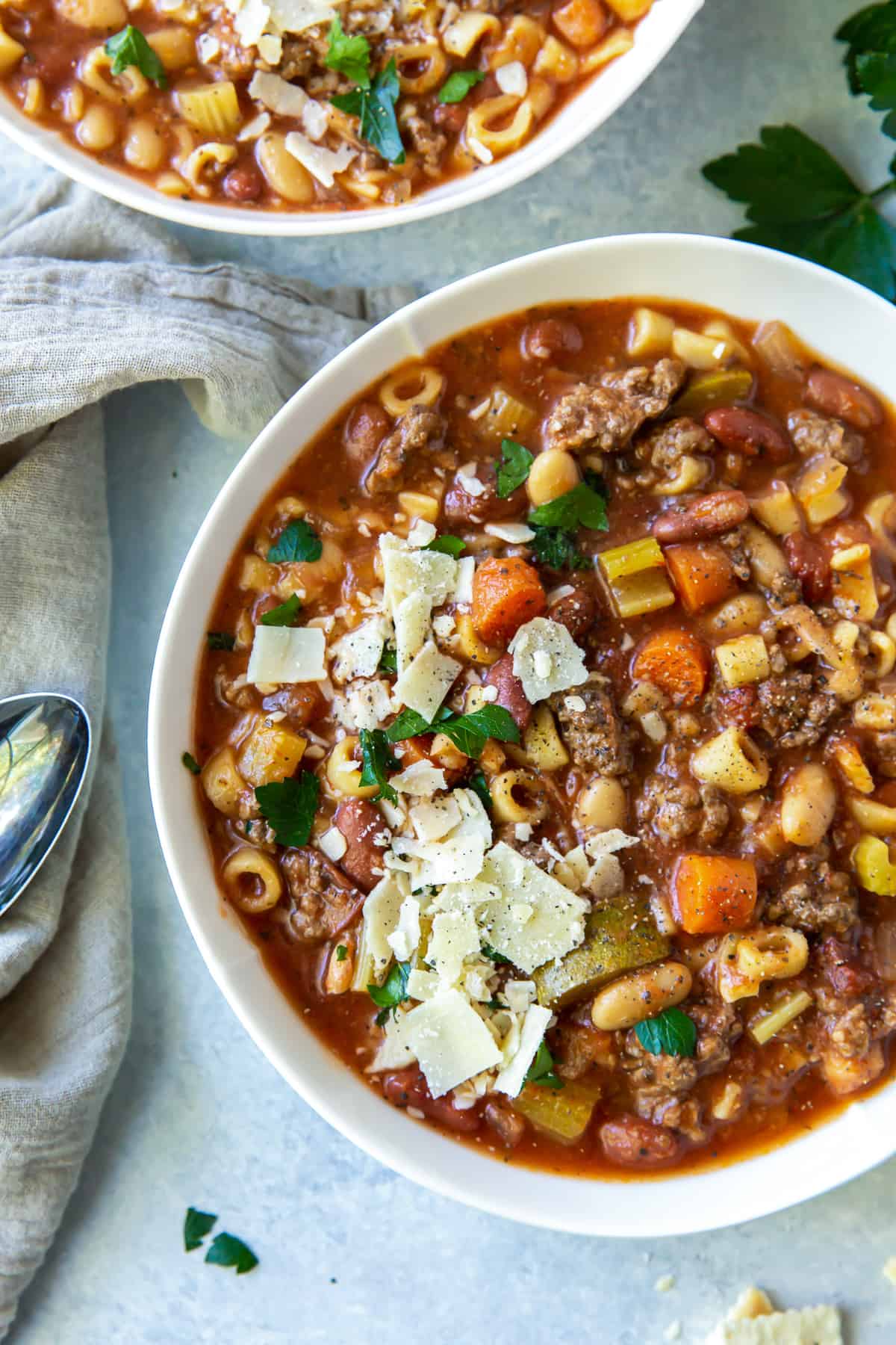 A close up, over the top shot of a bowl of hamburger minestrone topped with shaved Parmesan.