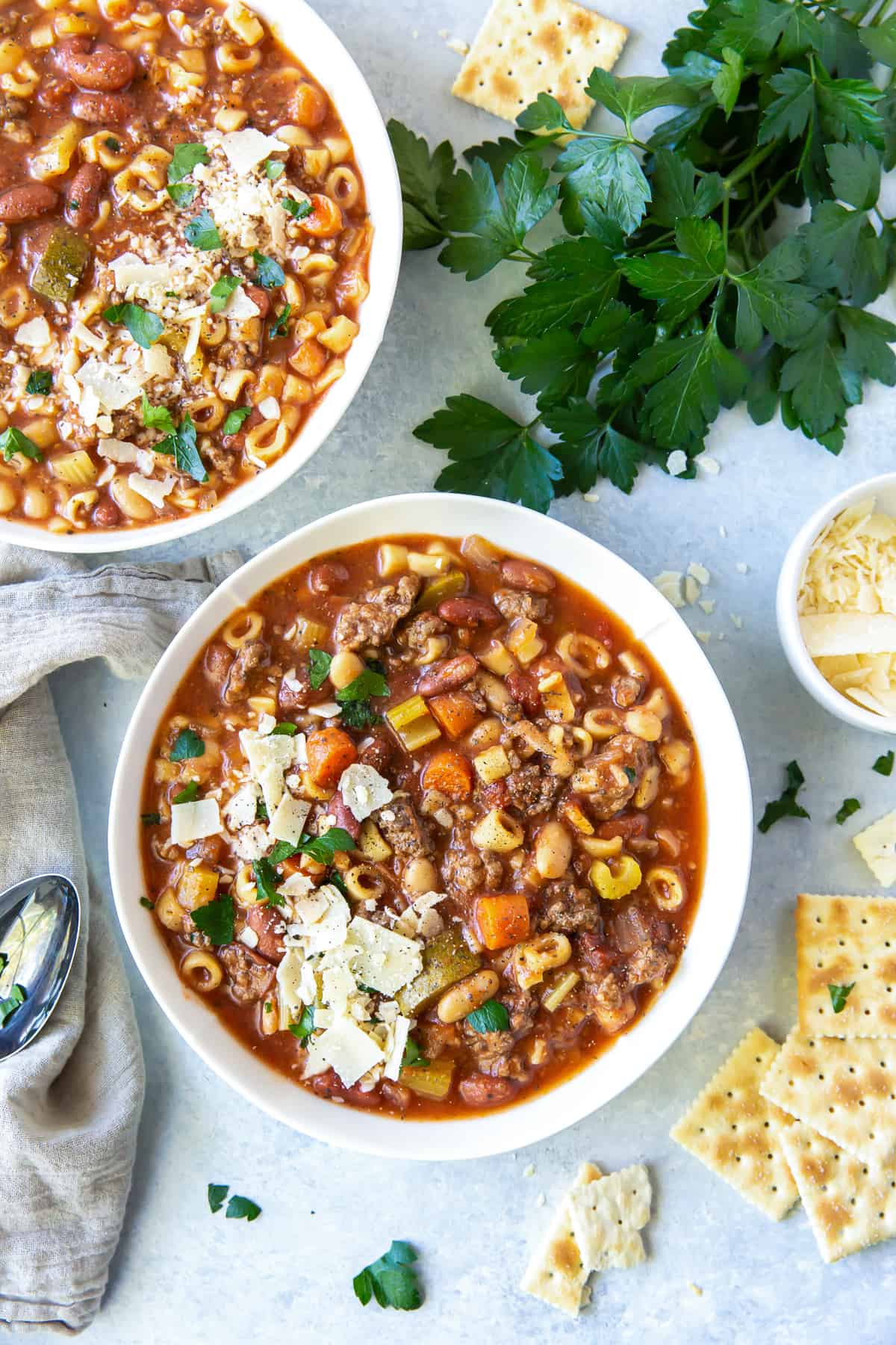 An over the top shot of two bowls of Hamburger Minestrone next to fresh parsley and saltine crackers.