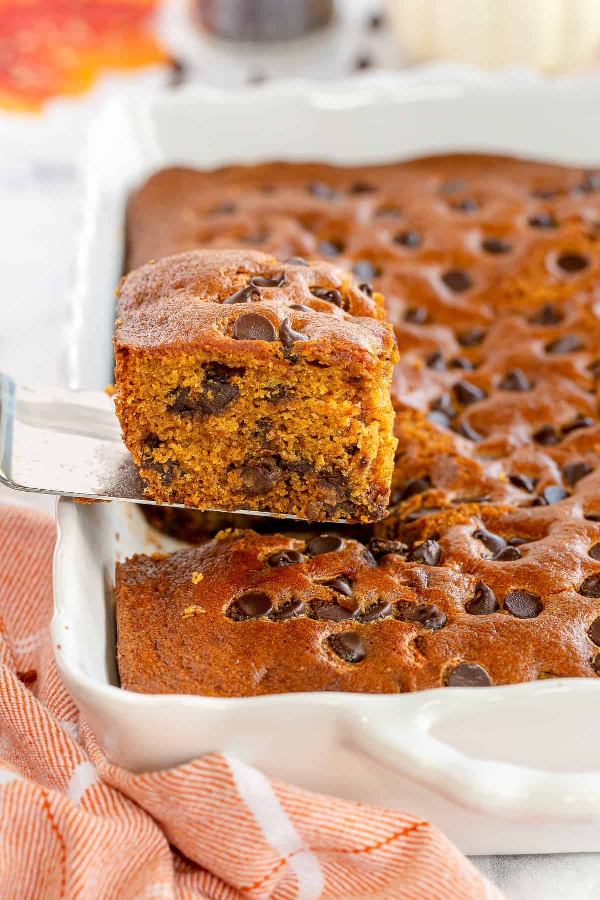 A spatula lifts a slice of cake from a baking dish.