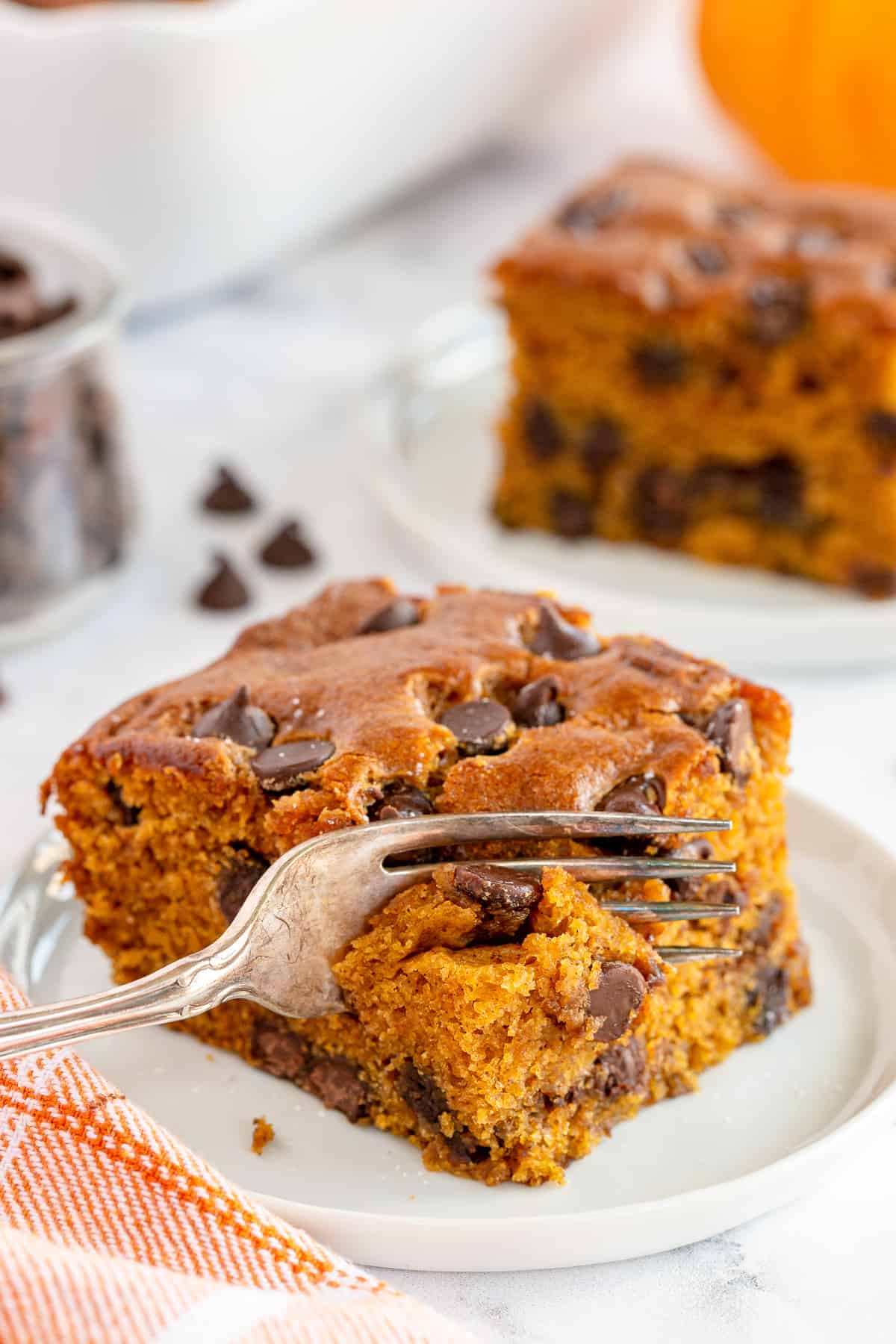 A fork presses into a slice of Pumpkin Chocolate Chip Cake.