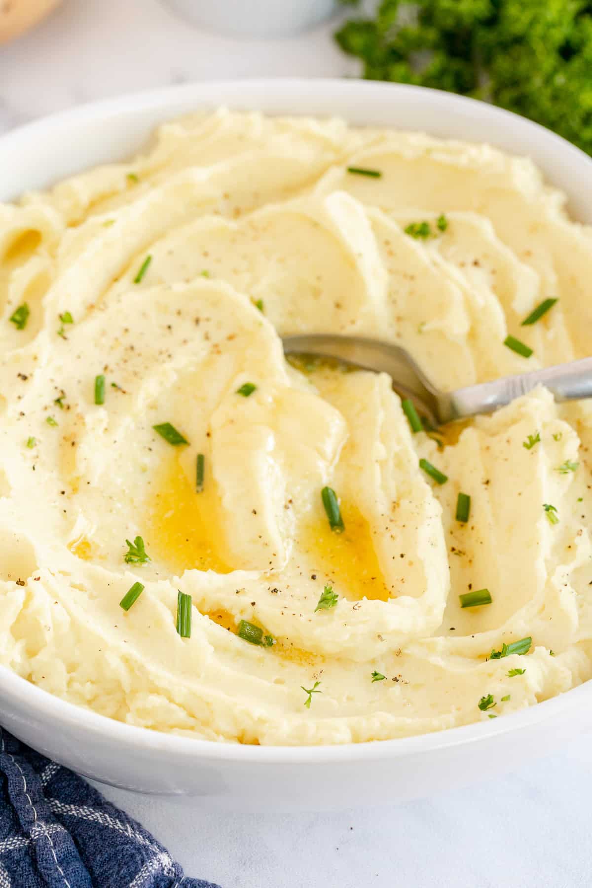 A white bowl filled with mashed potatoes topped with melted butter.