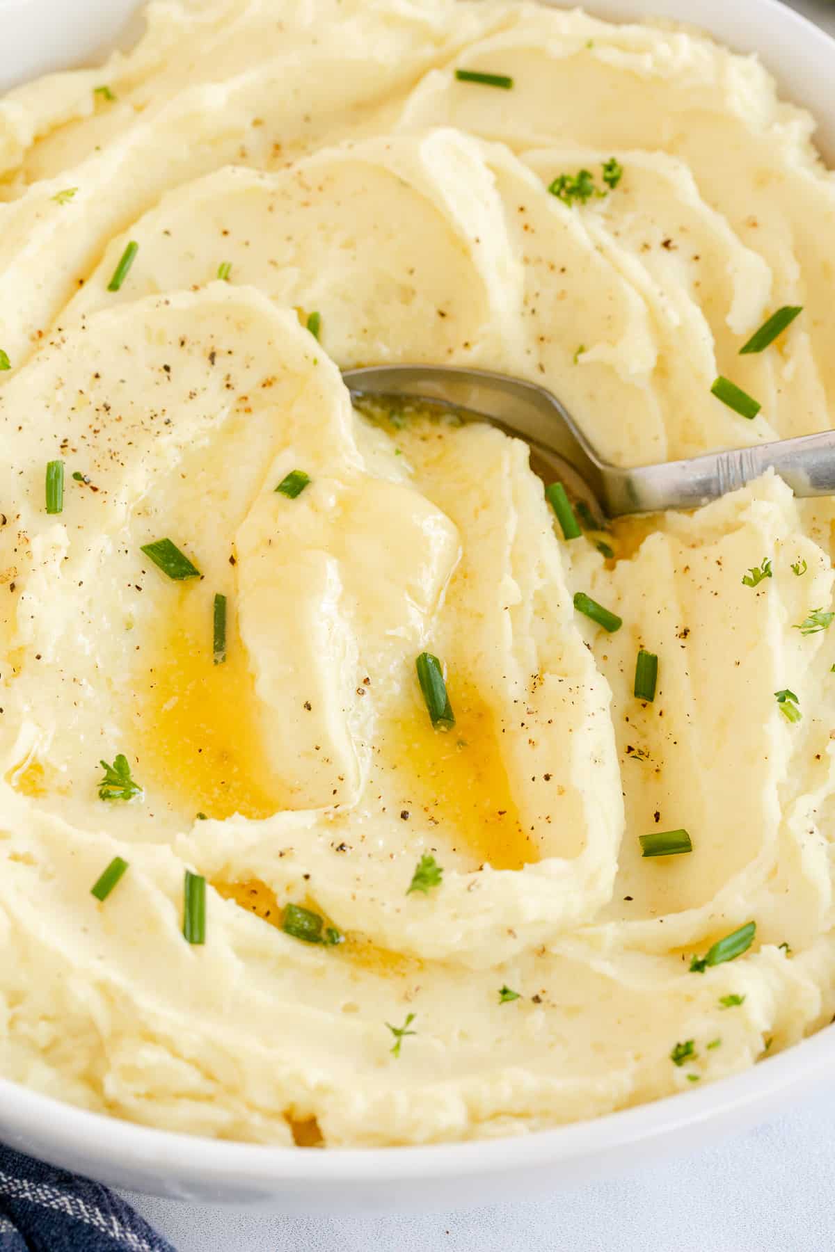 A close up of a spoon in a bowl of mashed potatoes.
