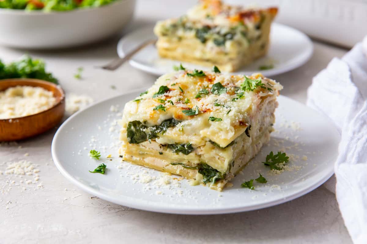 An eye level shot of a slice of White Chicken Lasagna on a white plate.