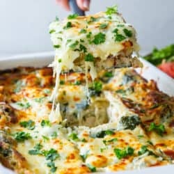 A spatula lifting a piece of lasagna from a baking dish.