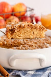 A slice of Apple Cider Coffee Cake is lifted from a baking dish.