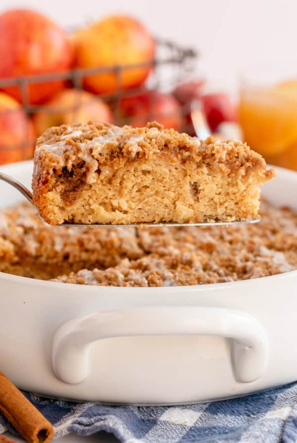 A slice of Apple Cider Coffee Cake is lifted from a baking dish.