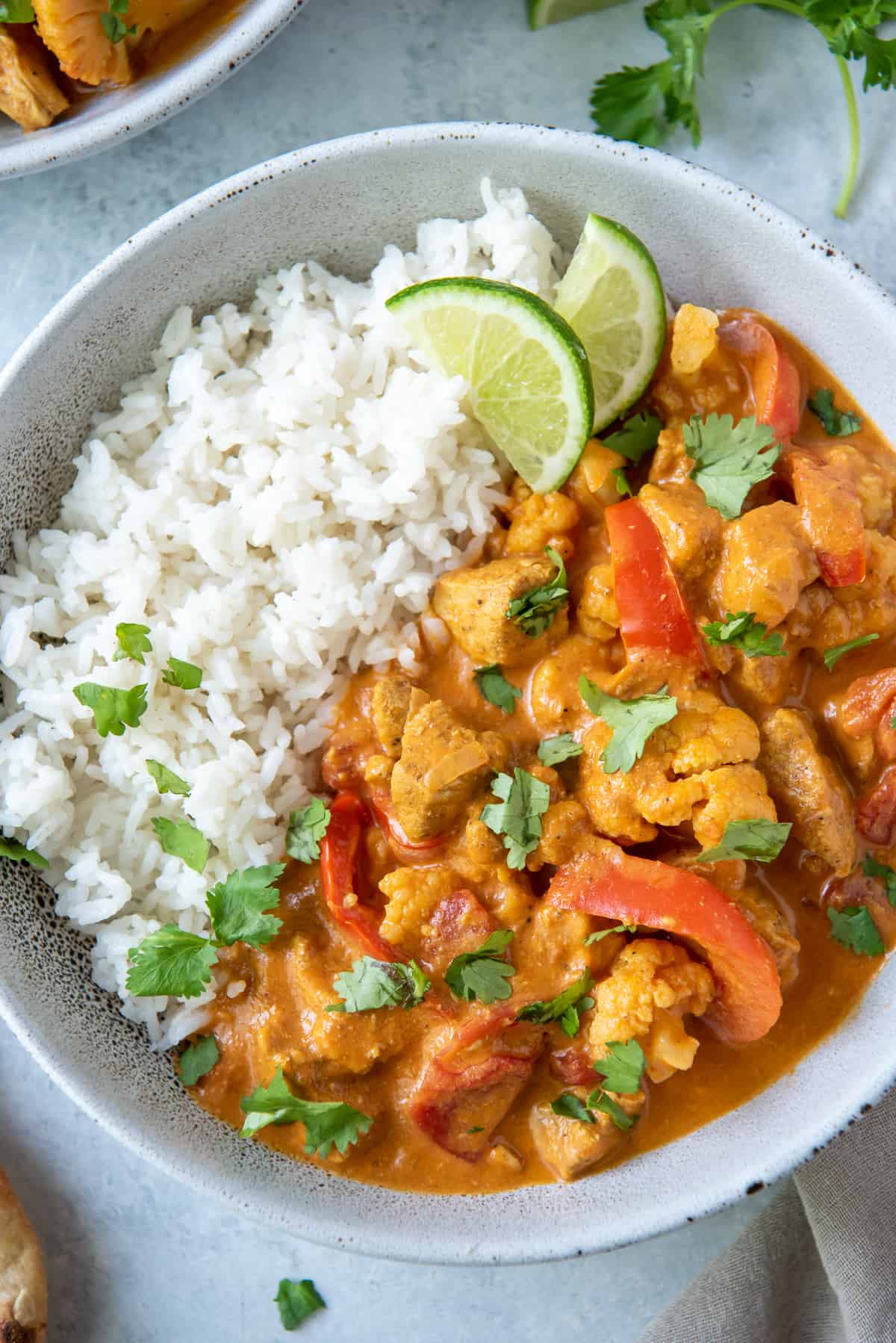 A close up over the top shot of curry chicken in a bowl with rice.