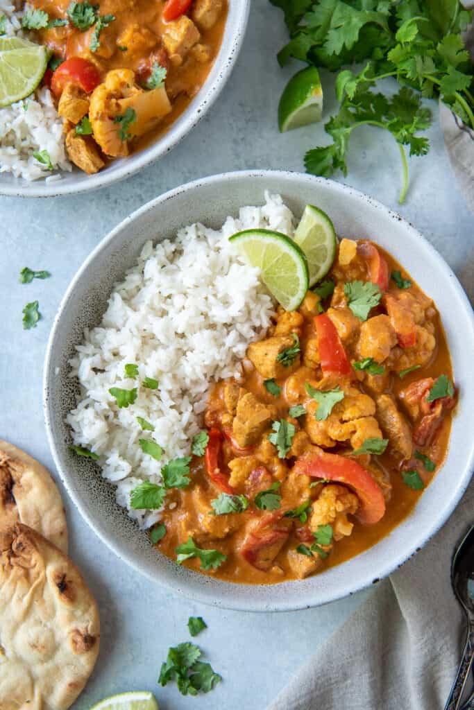 Coconut Curry Chicken in a bowl with rice and a lime wedge.
