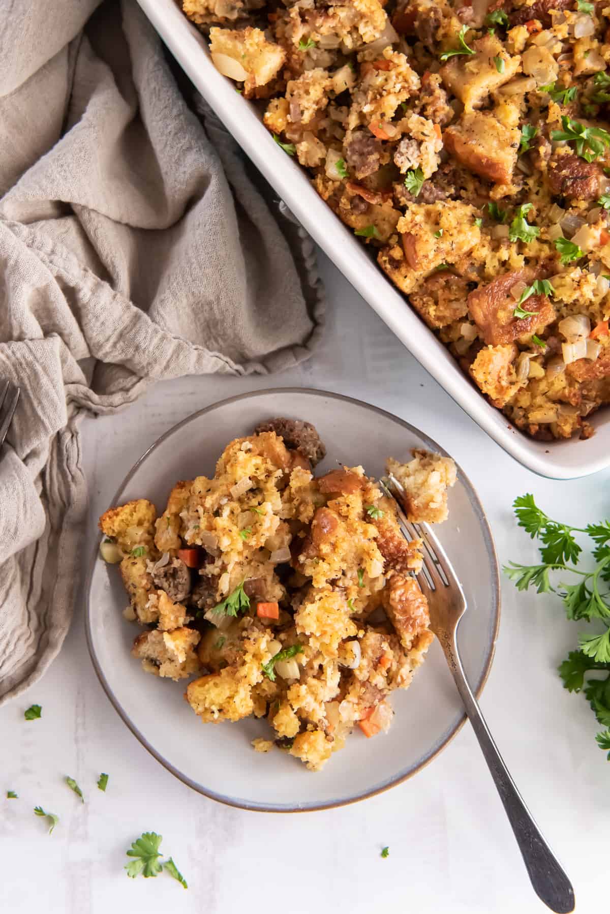 Cornbread stuffing on  small white plate and in a large baking dish.