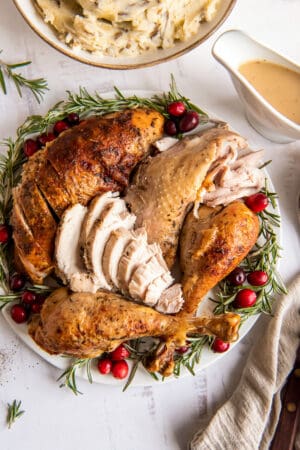 Turkey on a platter with rosemary and cranberries.