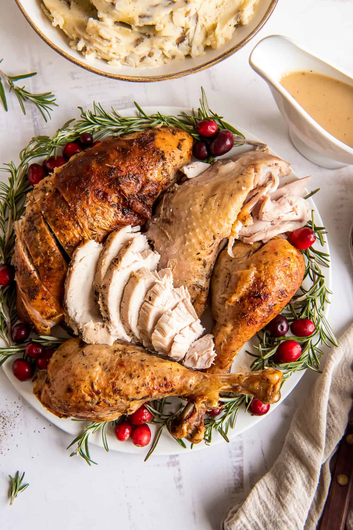 Turkey on a platter with rosemary and cranberries.
