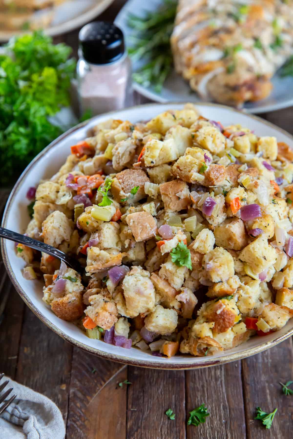 Stuffing in a white serving bowl with a spoon.