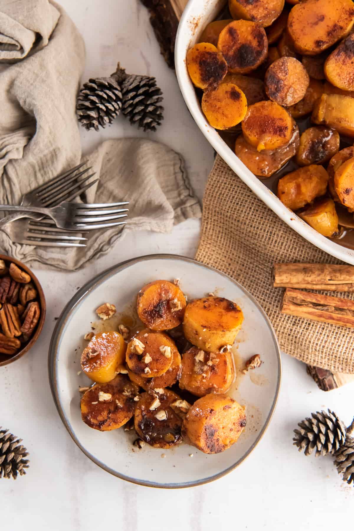 A serving of sweet potatoes on a small plate next to a baking dish.