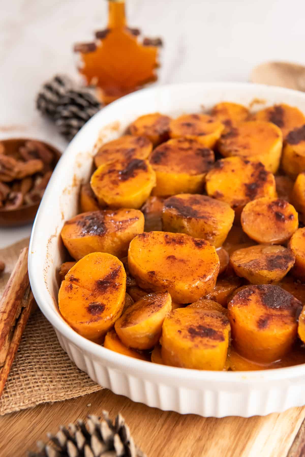 A white baking dish filled with sweet potatoes topped with cinnamon.
