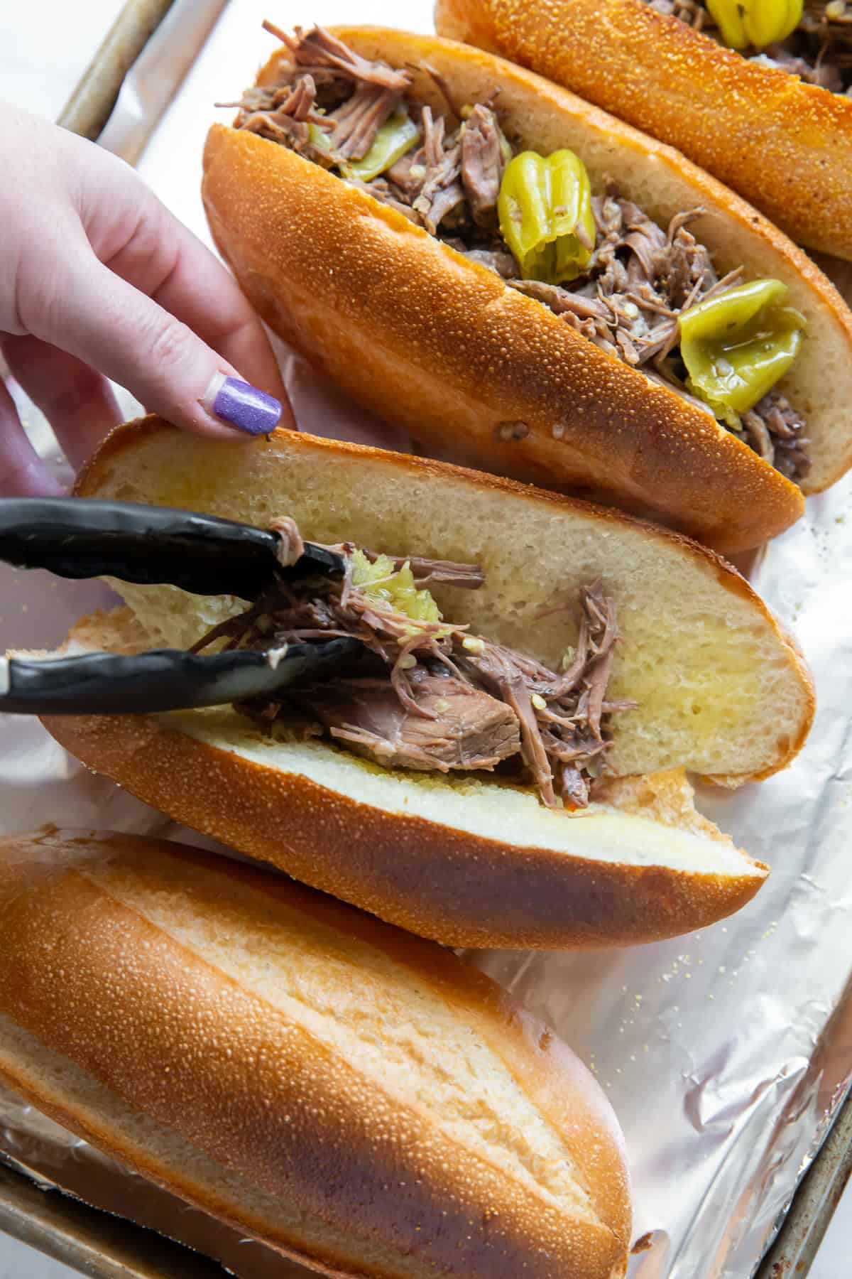 Filling hoagie rolls with shredded beef.