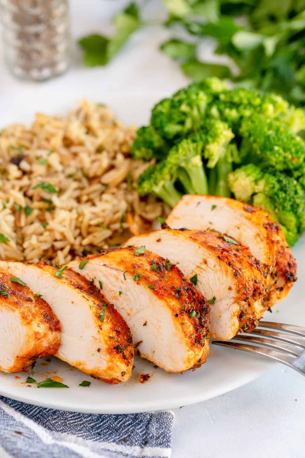 A sliced, cooked chicken breast on a plate with rice and a fork.