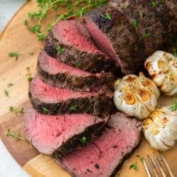 Sliced beef tenderloin on a wood board.