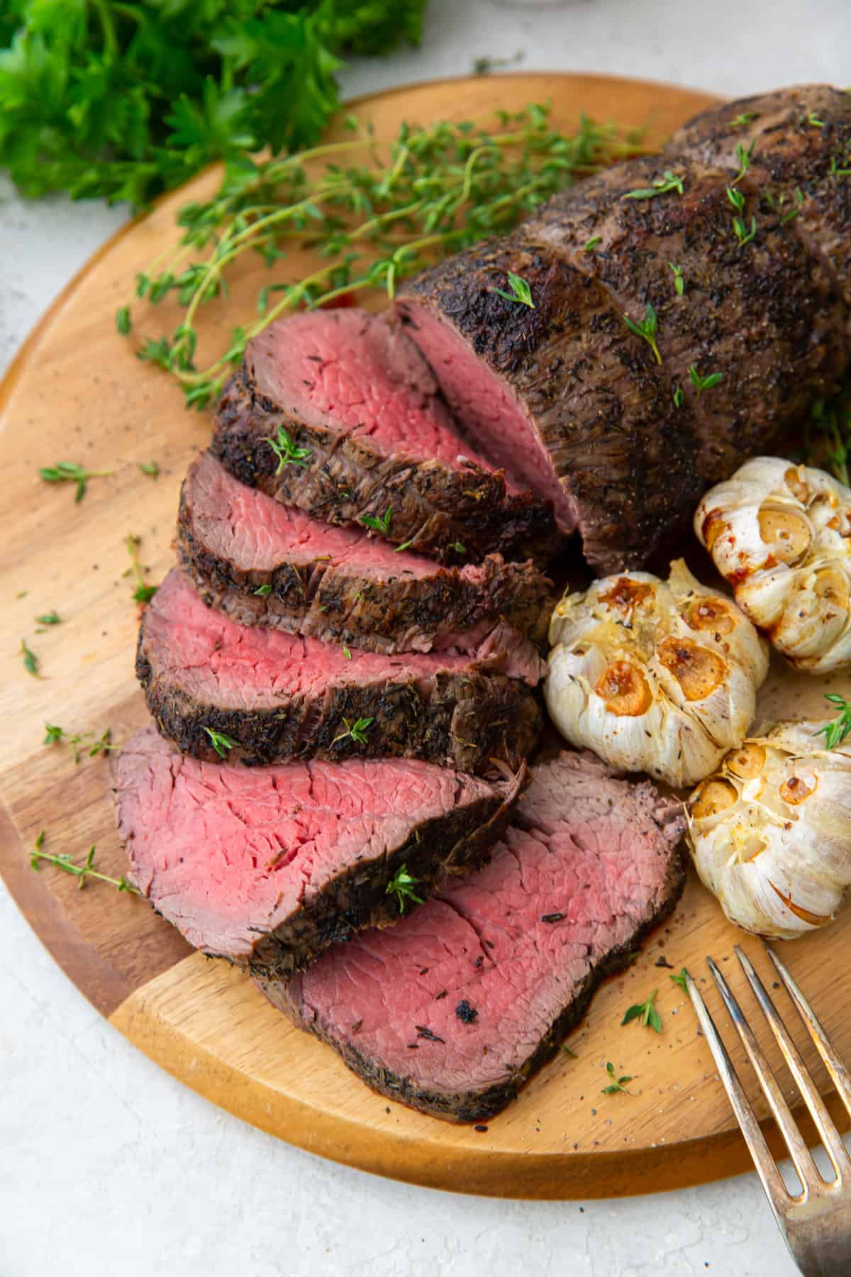 Sliced beef tenderloin on a wood board.