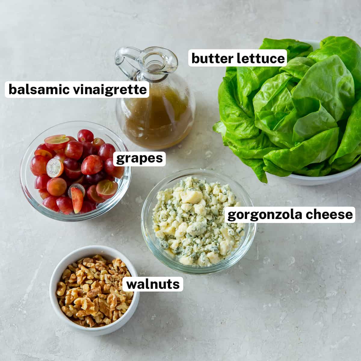 Butter lettuce, grapes, gorzonzola, walnuts, and dressing with overlay text.