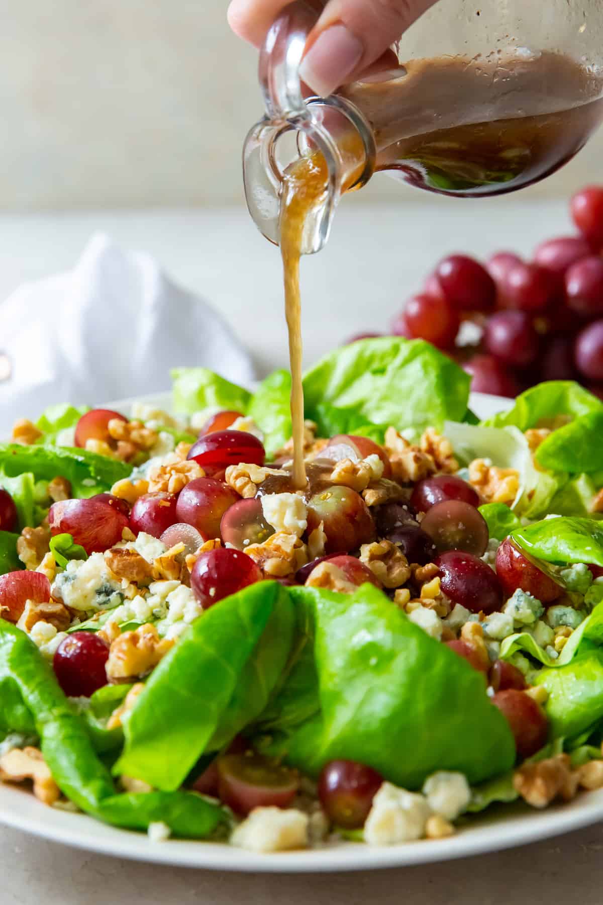 Balsamic vinaigrette pouring on to a butter lettuce salad.