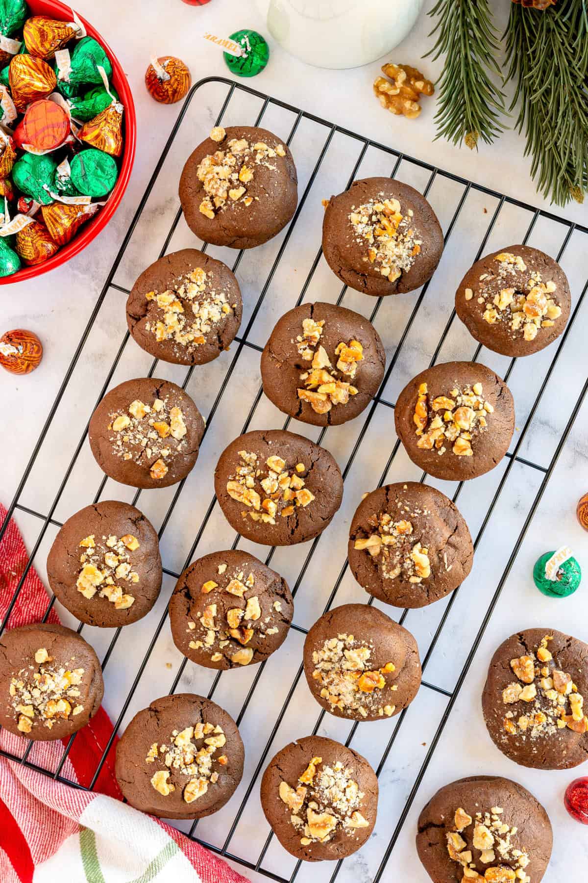 Chocolate cookies with walnuts cooling on a wire rack.