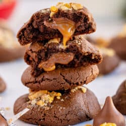 Caramel oozing out of a chocolate cookie on top of a stack.