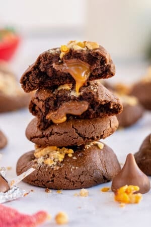 Caramel oozing out of a chocolate cookie on top of a stack.