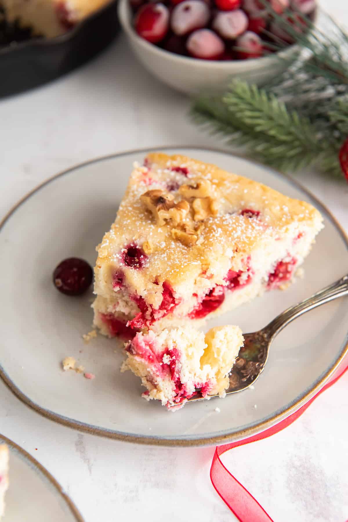 A fork pulls away a bite of cake on a white plate.