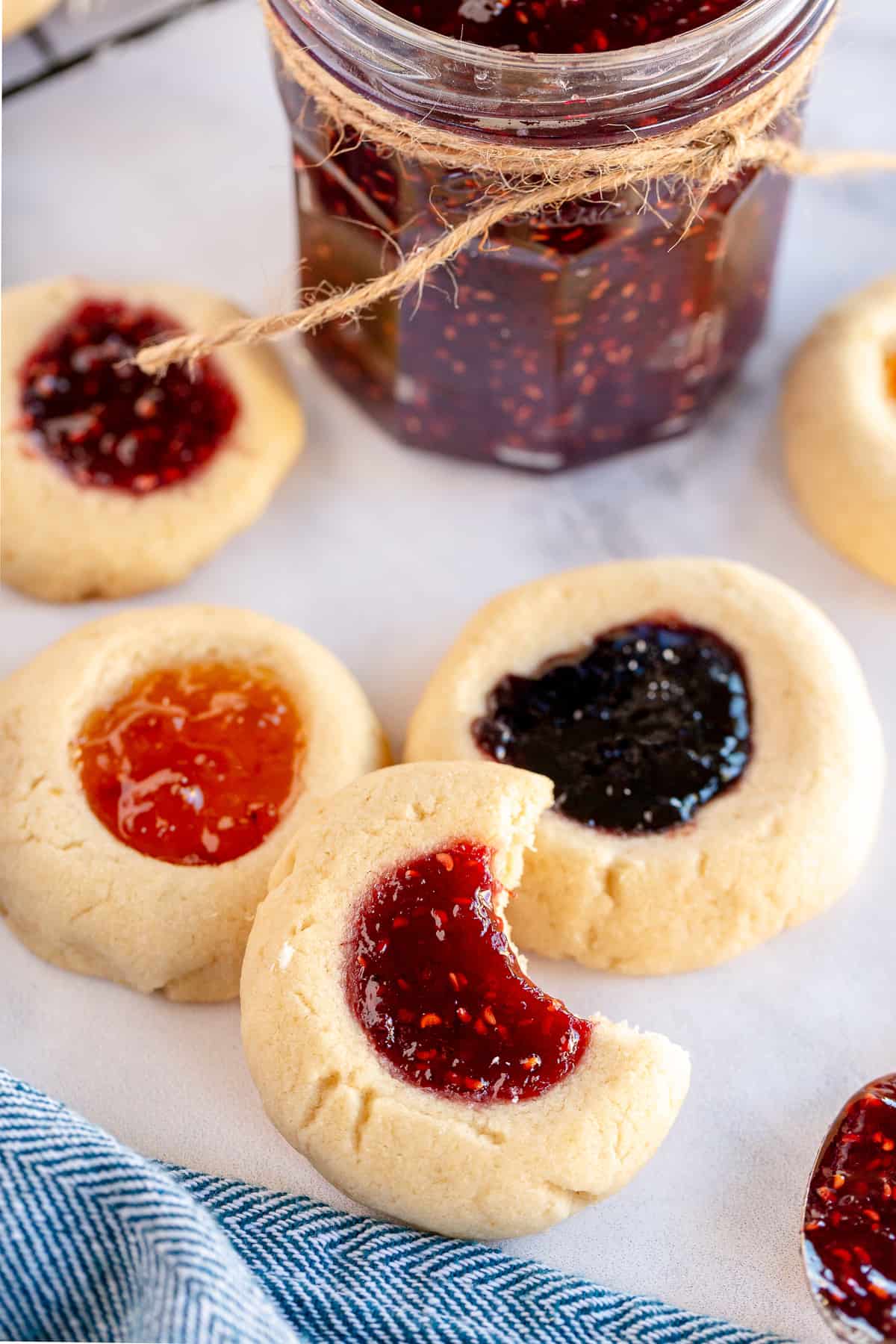 Four Jam Thumbprint Cookies and one with a bite missing.