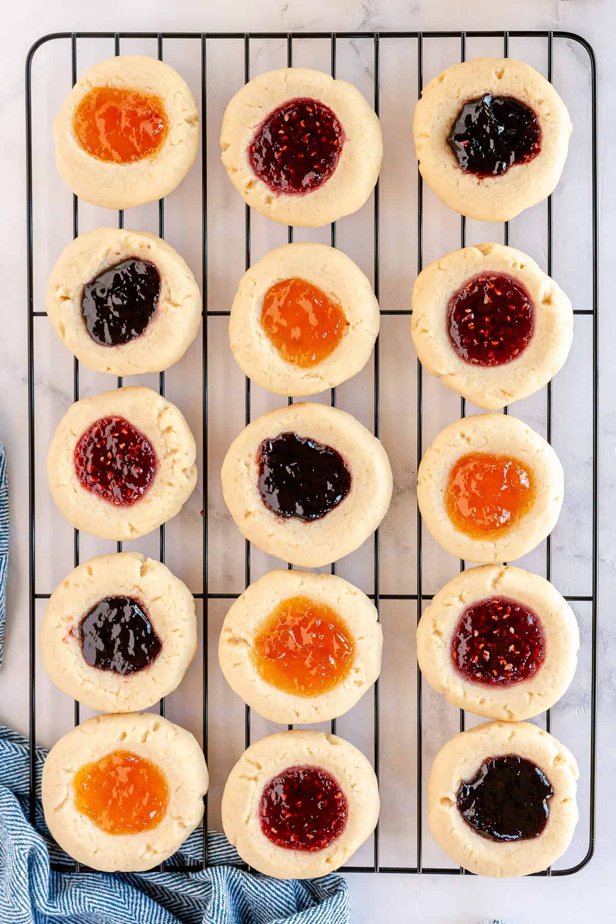 Jam filled thumbprint cookies cooling on a wire rack.