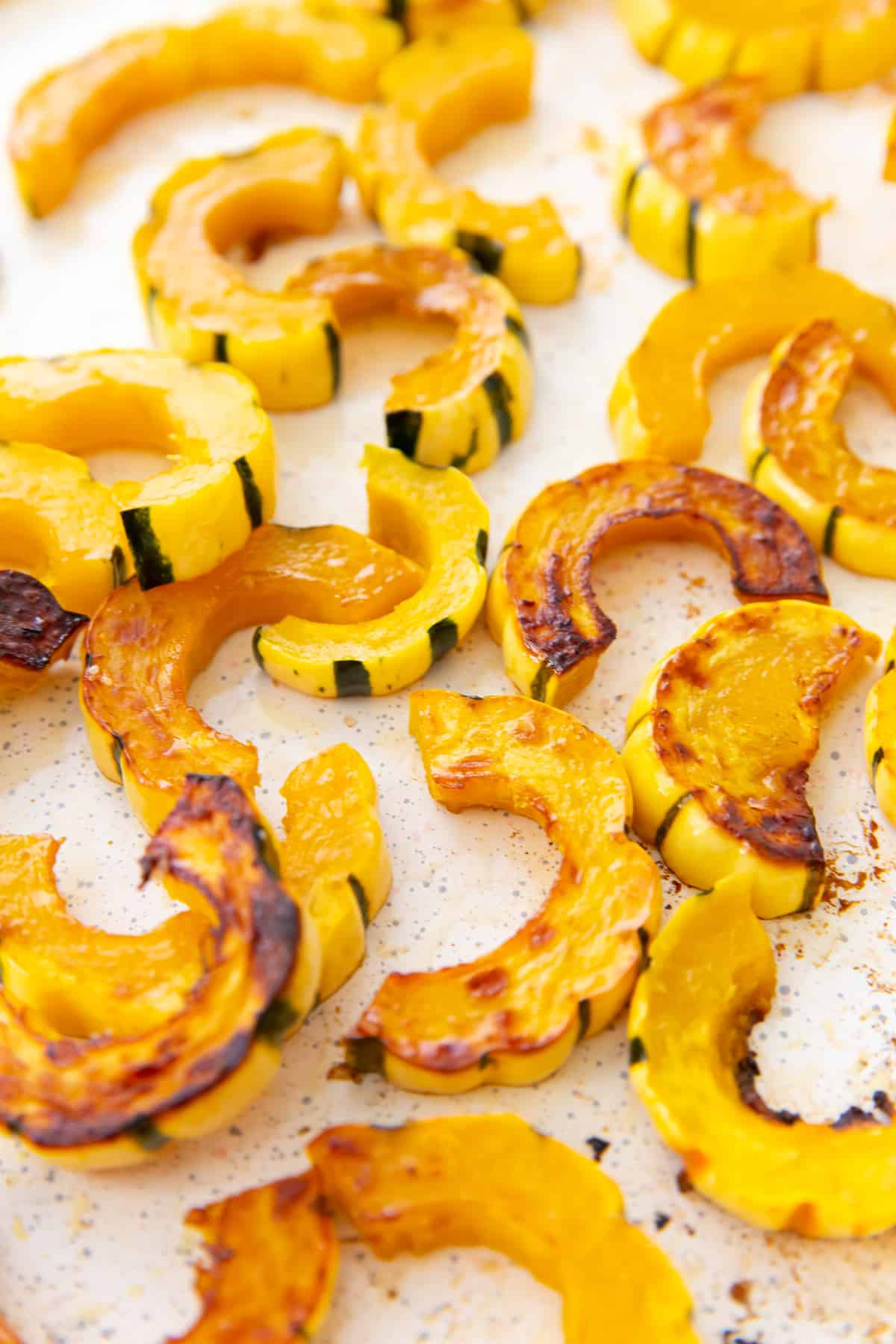 Sliced and roasted delicata squash on a baking sheet.