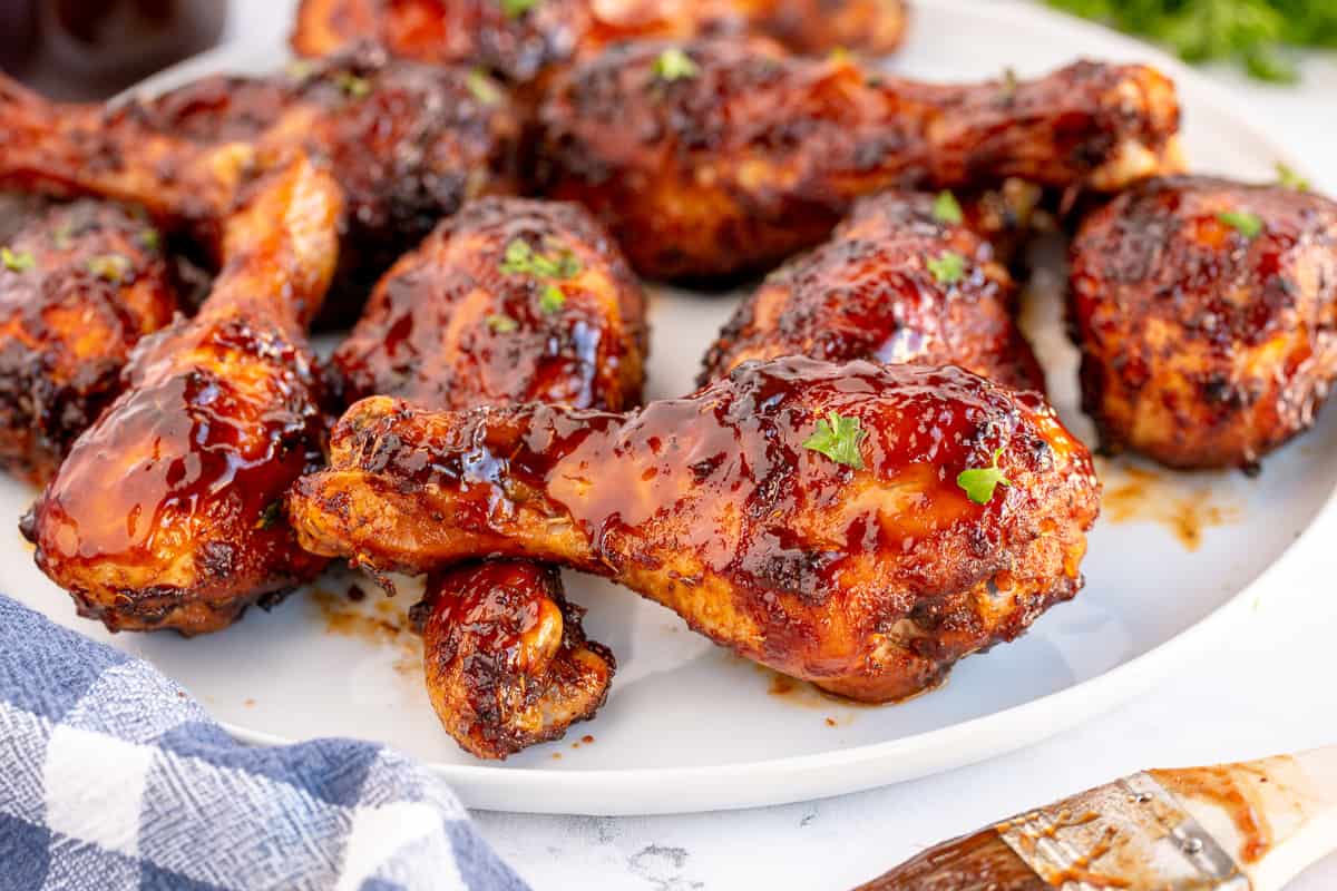 Chicken legs with BBQ sauce on a white plate.