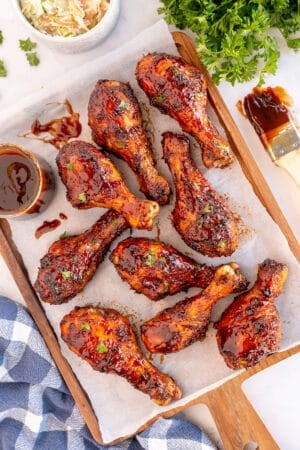 BBQ chicken drumsticks on a parchment paper lined board.